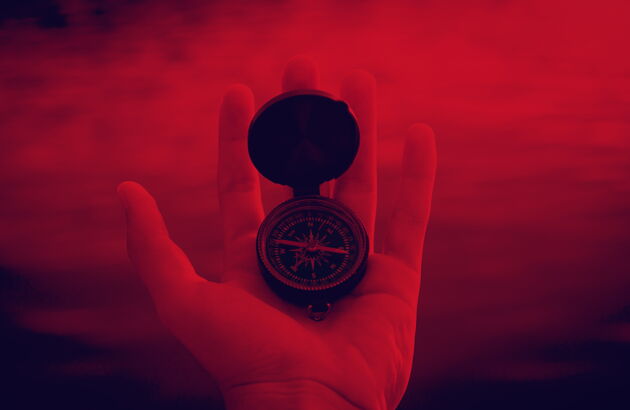 Rötliches Bild - Eine Person hält einen Kompass in der Hand.