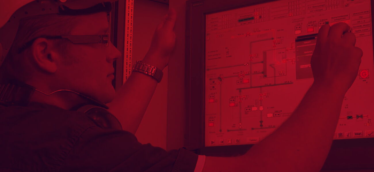 Rötliches Bild - Ein Mann schaut auf eine Leittechnik auf einem Bildschirm.